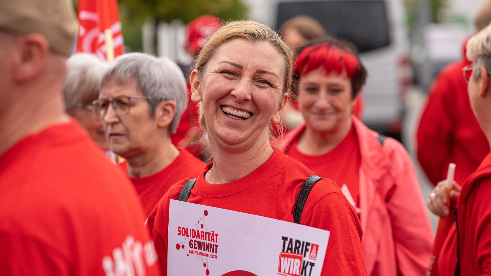 Eine Frau im roten T-Shirt lächelt in die Kamera.